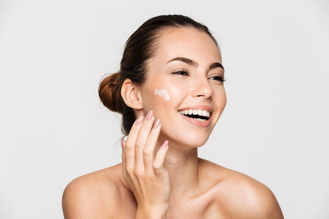 onna con pelle luminosa e sana che applica una crema viso a base di bava di lumaca